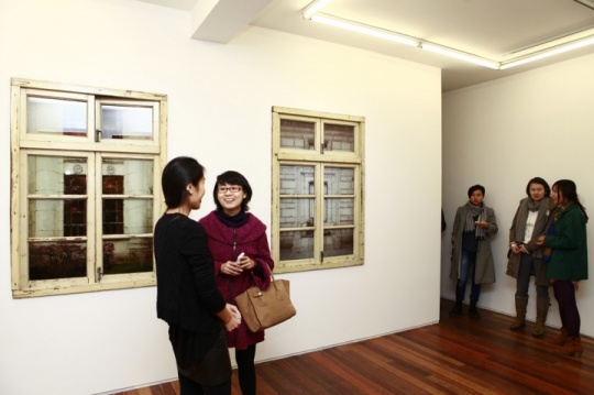 觀眾在李青個展“若比鄰”現(xiàn)場交流，背后為其新作《鄰窗·英倫風(fēng)》、《鄰窗·圣彼得堡風(fēng)》
