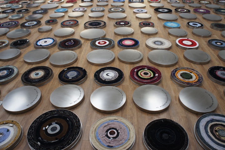《一句話》裝置   不同人穿過(guò)的衣服、不銹鋼 2011  （橫濱三年展） ，尹秀珍將108件個(gè)人的衣服拆開，再重新纏繞成電影膠卷一樣的卷軸，放在擺放成螺旋形的圓盒中。
