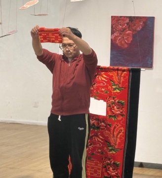 開幕式尹小龍現(xiàn)場藝術(shù)作品《紐帶的線索》手舉剪下的喜字,使用的材料是當(dāng)年父母結(jié)婚時(shí)用的被單
